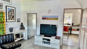 A modern living room with a flat-screen TV, a sofa, a coffee table, and a dining area with a table and chairs. - Cosy City Apartment Near Station, City Centre (Alkmaar)