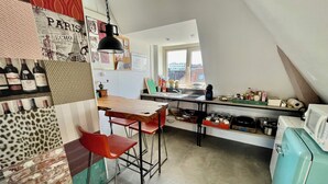 A compact kitchen with a wooden table, red bar stools, a vintage refrigerator, and various kitchen items. - Cosy City Apartment Near Station, City Centre (Alkmaar)