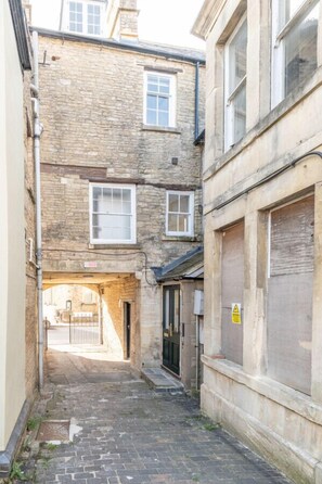 Une ruelle étroite, bordée de bâtiments en pierre, avec un chemin pavé de briques.