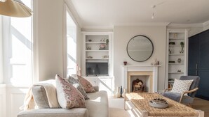 Una sala de estar con sofá, sillones, una mesa de centro, chimenea y estanterías empotradas.