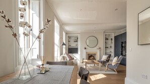 Un salón espacioso con chimenea, un comedor con mantel a rayas y una cocina al fondo.