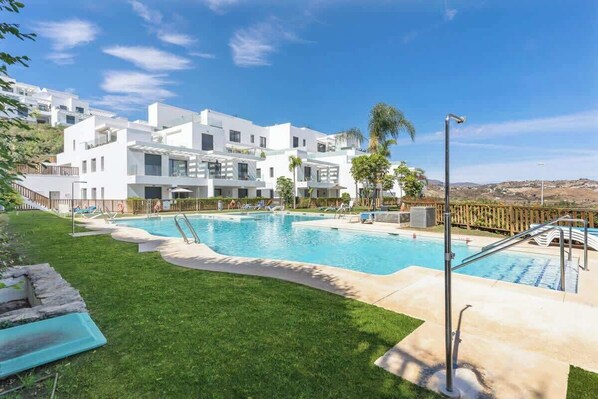Un hotel moderno con piscina, un prato curato e vista sul paesaggio circostante.