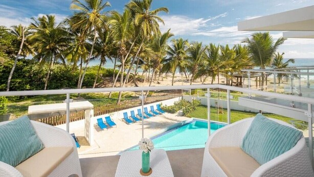 Un balcon avec vue sur une piscine, des chaises longues et des palmiers.