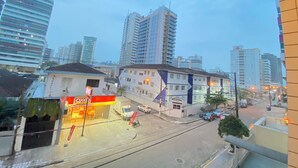 A cityscape with tall buildings, a gas station, and a street with parked cars.