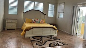 Una camera da letto con un letto, un comodino, una porta e una finestra.