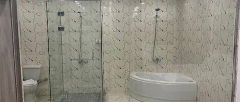 A modern bathroom with a glass-enclosed shower, a white bathtub, and marble-patterned walls.