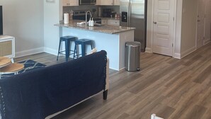 A modern kitchen with white cabinets, a stainless steel refrigerator, and a microwave.