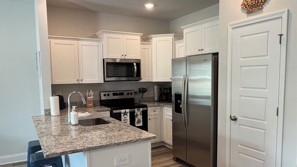 A modern kitchen with white cabinets, stainless steel appliances, and a granite countertop.