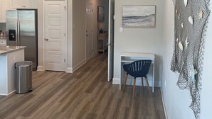 A modern kitchen with white cabinets, a stainless steel refrigerator, and a wooden dining table.