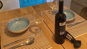 A dining table with a bottle of wine, two wine glasses, and a bowl.
