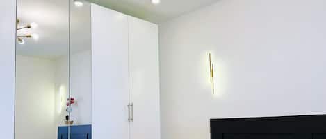 A modern bedroom with a large bed, a mirrored wardrobe, and a ceiling light fixture.