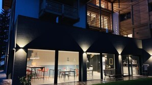 A modern house with a dining area, kitchen, and outdoor seating. - CASA ESTER (Baselga di Pine)