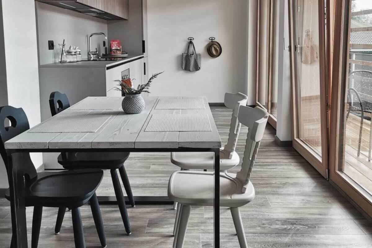 Un espace repas moderne avec une table rectangulaire, des chaises noires et blanches, et des luminaires suspendus.