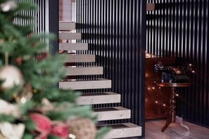 Una escalera moderna con escalones de madera y una pared oscura con líneas verticales.