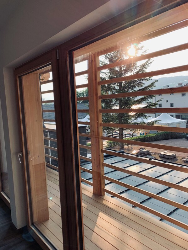 Un balcón de madera con vistas a una zona residencial, con casas y árboles.
