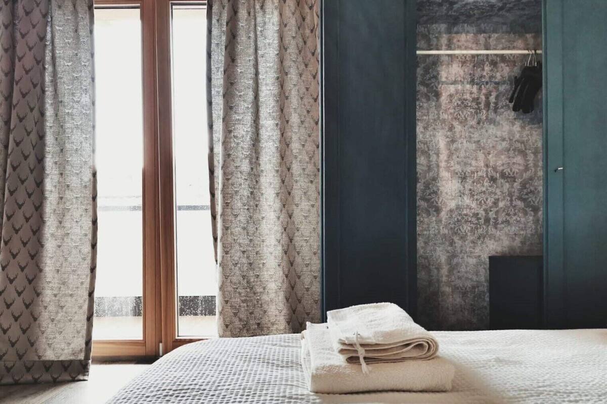 Une chambre à coucher avec un lit, une fenêtre avec des rideaux, une armoire et une serviette sur le lit.