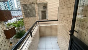 A narrow corridor with tiled walls and a metal railing, leading to a door with a small window. - Foot on the sand beach of Guilhermina III (Praia Grande)