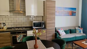 Un salon moderne avec un canapé vert, une table basse et un coin repas comprenant une table et des chaises.