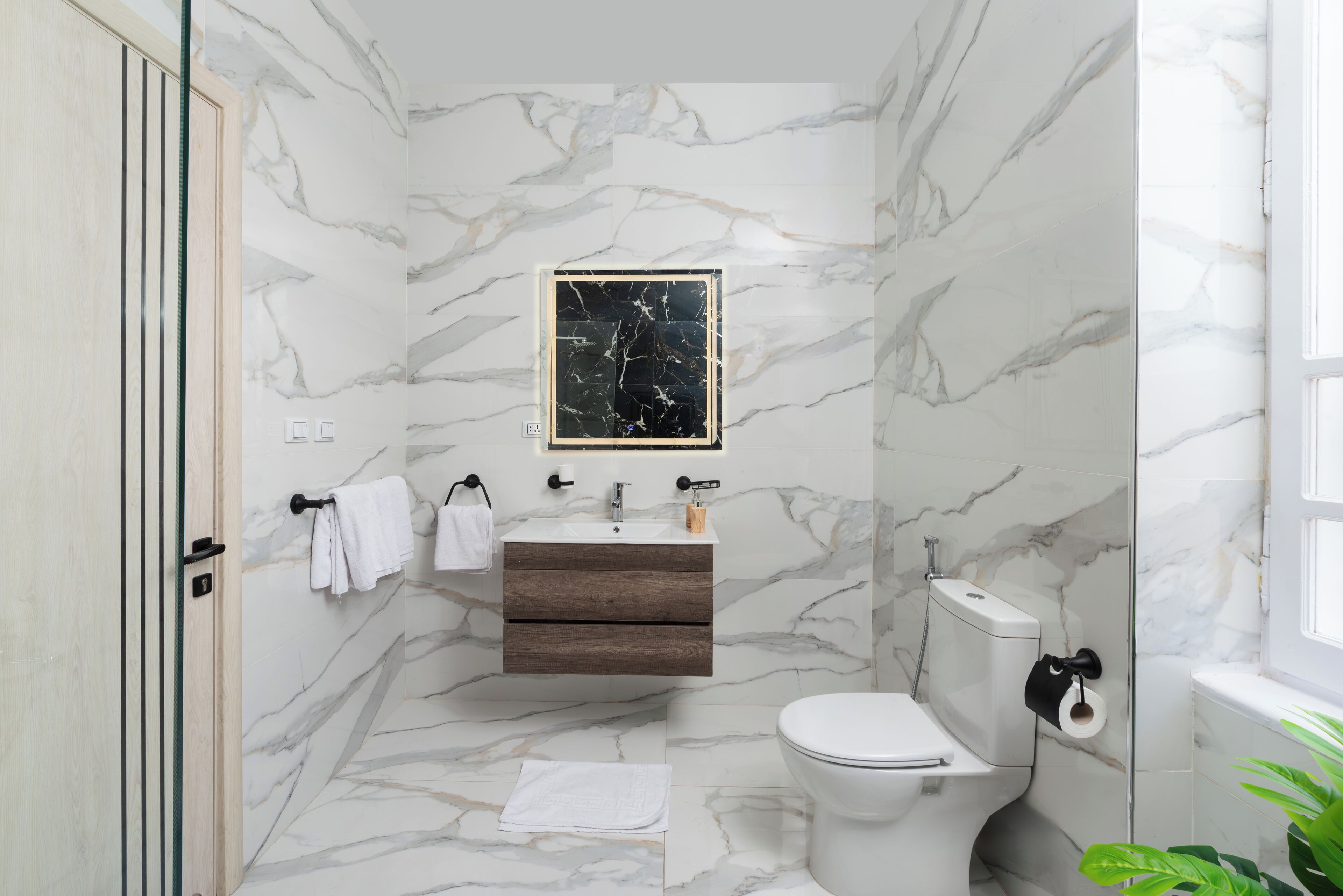 Ein Badezimmer mit Marmorwand, einem Holzkosmetikschrank, einer Toilette und einem Fenster.