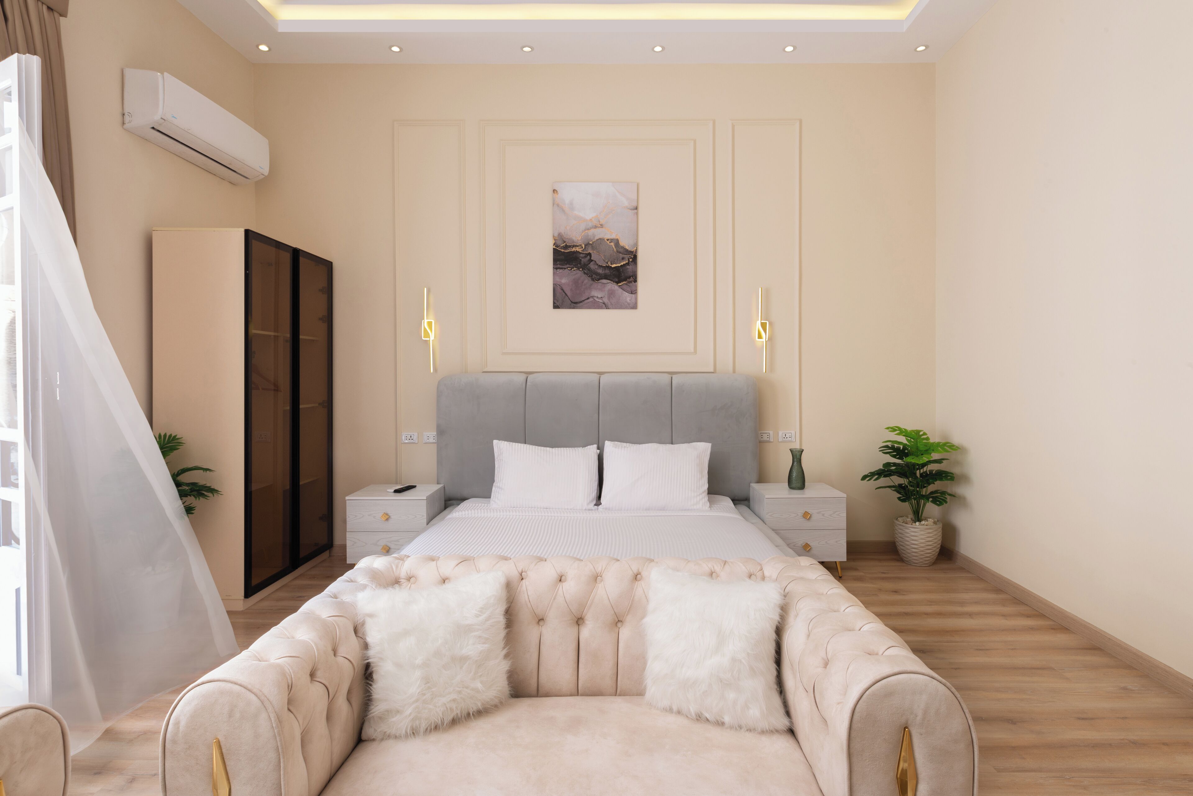 Un dormitorio moderno con una cama grande, mesitas de noche, un armario y una planta decorativa.