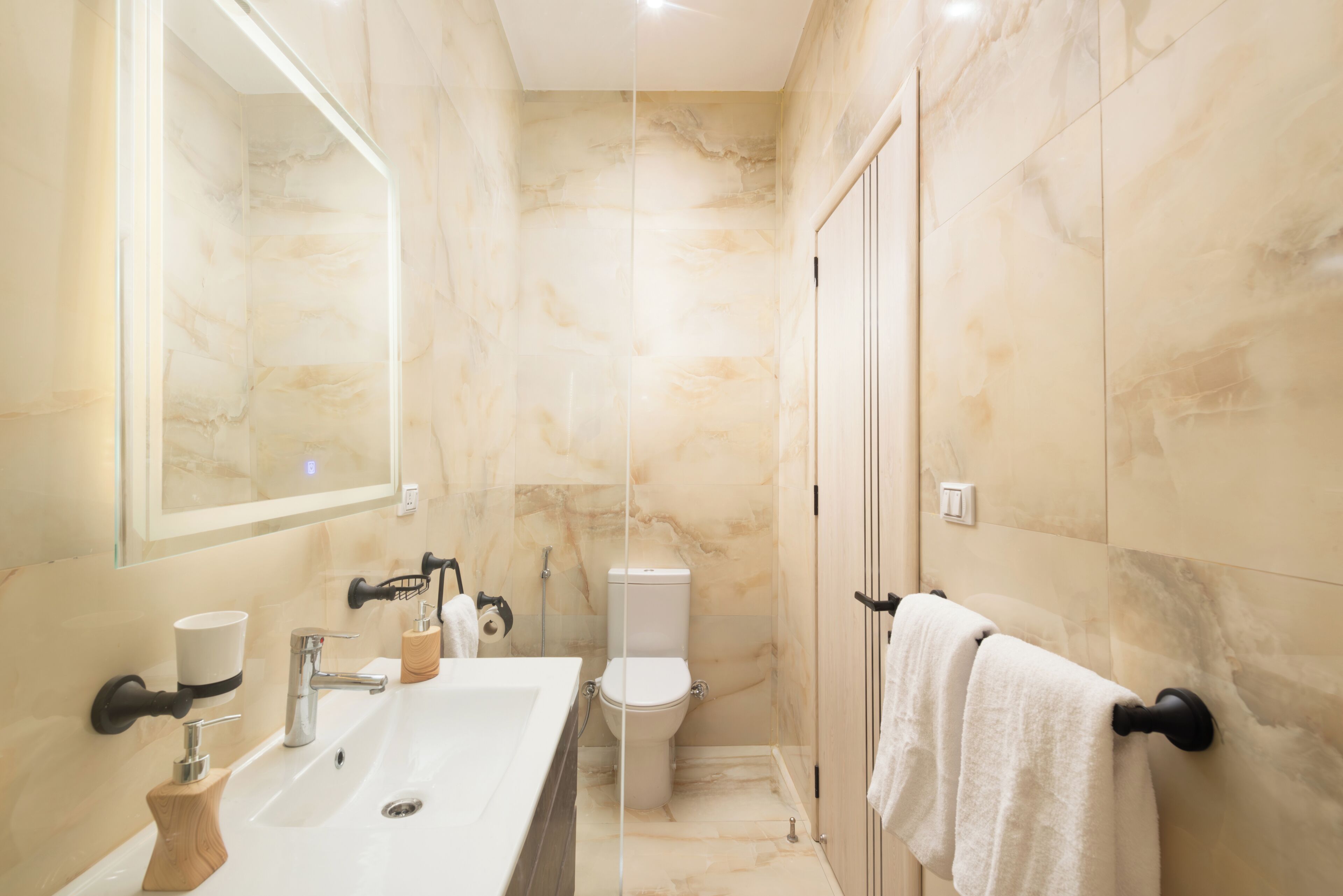A modern bathroom with a marble sink, toilet, and shower.