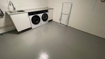 A compact laundry area with a washing machine, a sink, and a drying rack.