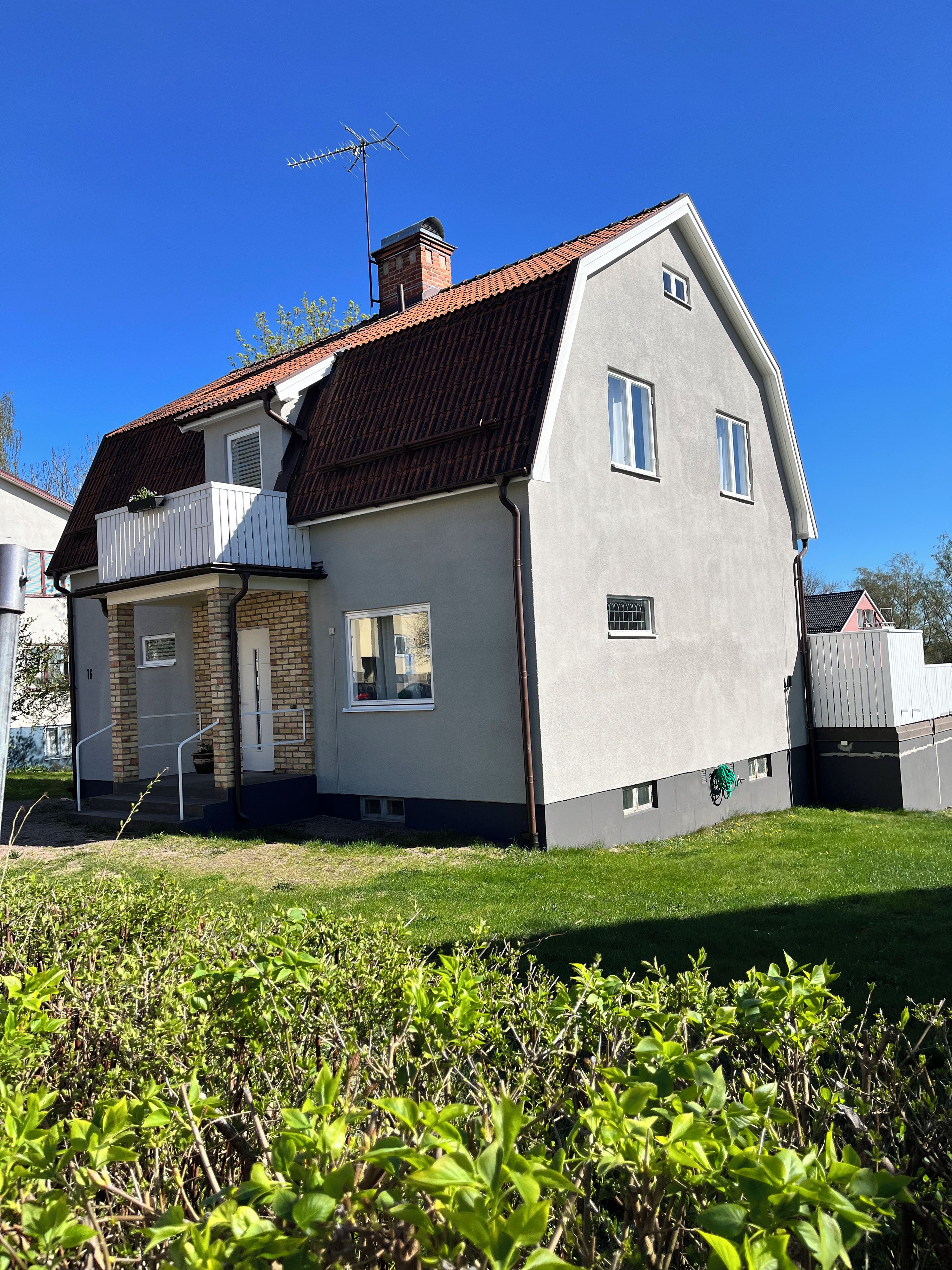 A two-story house with a sloped roof, a balcony, and a chimney.