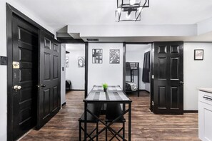 A room with a checkered table, a potted plant, and a bunk bed in the background.