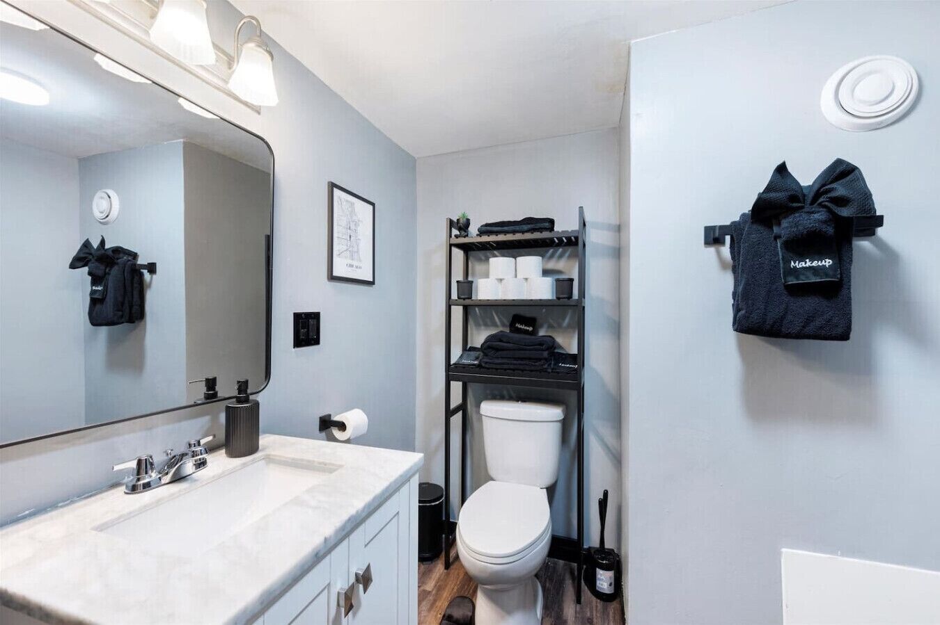 Une petite salle de bain comprenant un lavabo, des toilettes et des étagères où sont rangés les articles de toilette.