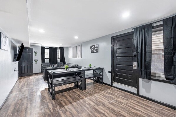 A modern room with a wooden floor, a black door, and a window with curtains.