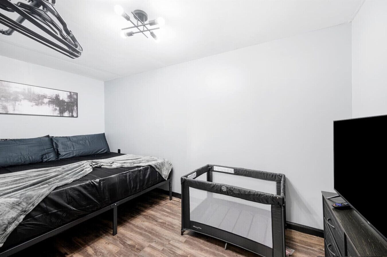 A room with a bed, a TV, and a ceiling fan.