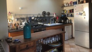 Une cuisine dotée d’un îlot central, d’appareils électroménagers en acier inoxydable et d’un réfrigérateur orné d’aimants et de petits mots.