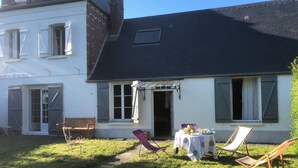 Une maison avec un jardin, une table avec des chaises et un banc.