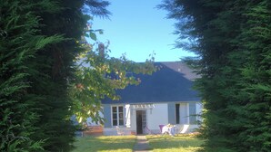 Une maison avec un chemin menant à la porte d’entrée, entourée d’arbres verdoyants et touffus.