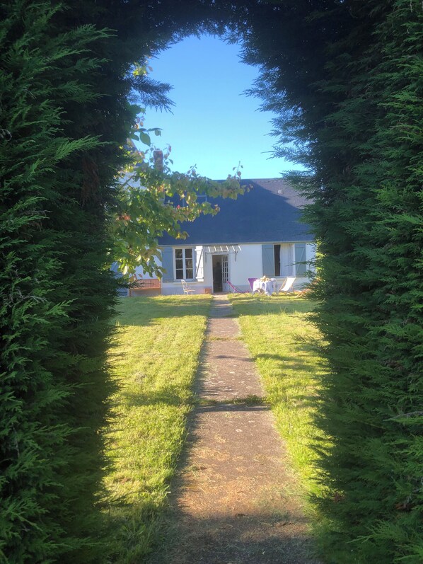 Une maison avec un chemin menant à la porte d’entrée, entourée d’arbres verdoyants et touffus.