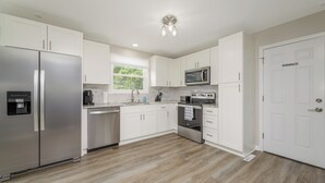 Una cocina moderna con armarios blancos, electrodomésticos de acero inoxidable y piso de madera.