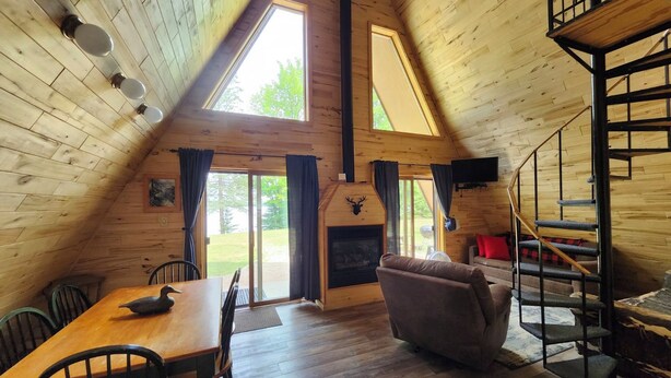 Ein gemütliches Cabin-Interieur mit Holzboden, Kamin, Essbereich und Treppe.