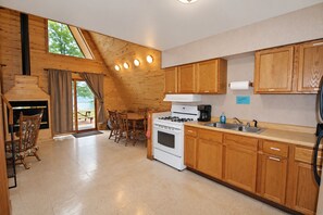 A kitchen with wooden cabinets, a stove, and a dining area with chairs.