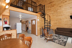 A wooden interior with a dining area, kitchen, and living space, including a spiral staircase.