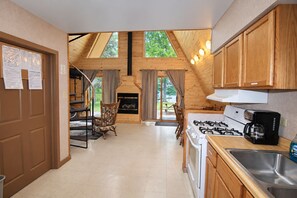 A kitchen with a gas stove, a coffee maker, and wooden cabinets.