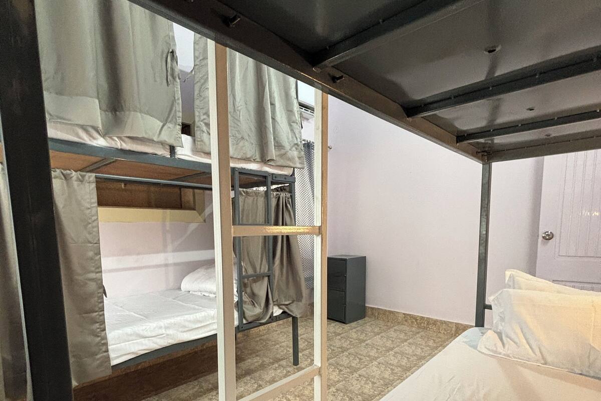 A bunk bed room with a ladder, a small cabinet, and a door.