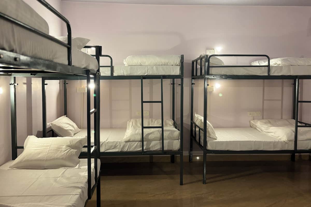 A bunk bed room with four beds, each with white bedding and a ladder.
