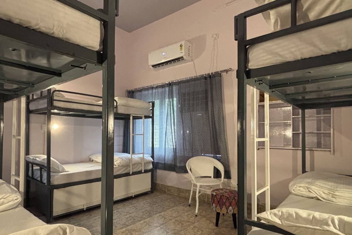 A dormitory room with bunk beds, a small table, and a chair.