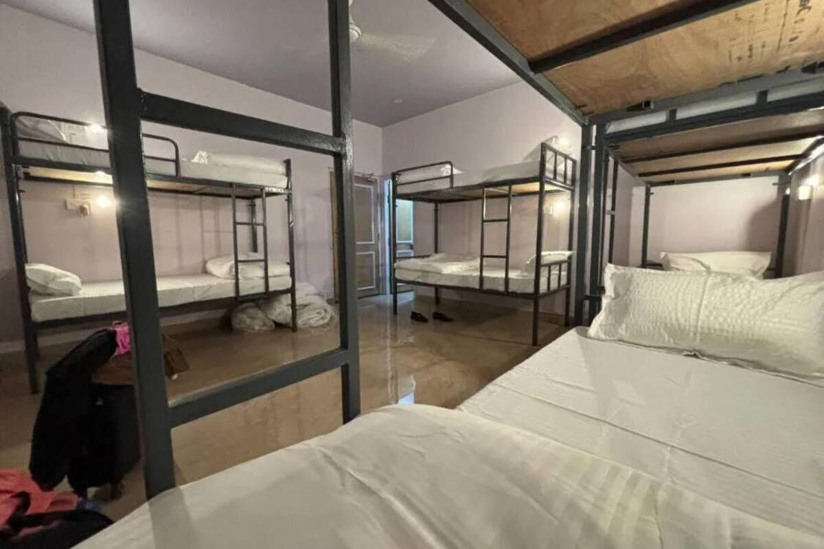 A dormitory room with bunk beds, a wooden ceiling, and a mirror on the wall.