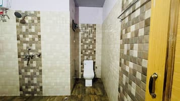 Un baño con inodoro, ducha y paredes con azulejos.