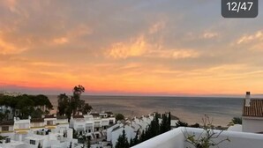 Un pueblo costero con edificios blancos y vistas al mar al atardecer.