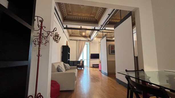 A spacious living area with a wooden floor, a glass dining table, and a modern sofa. - Aure (Verona)