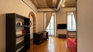 A living room with a wooden floor, a red sofa, a black entertainment unit, and a large mirror on the wall. - Aure (Verona)