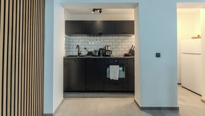 Una cocina moderna con armarios negros, un salpicadero blanco de azulejos y un horno empotrado.