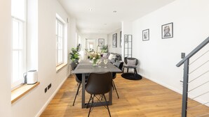 Un comedor espacioso con una mesa larga, sillas modernas y una escalera que sube a un nivel superior.